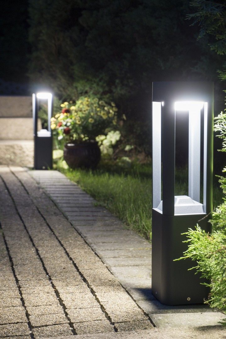 Lampa stojąca ogrodowa Fan Kwadrat H50 w kolorze czarnym, z prostokątnym korpusem i przezroczystymi panelami. Ujęcie z boku, na tle ścieżki i roślinności, podkreślające oświetlenie otoczenia. Wysokość lampy 50 cm, 1-punktowe źródło światła.