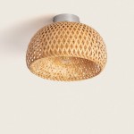 Plafon Mia mini z bambusa w naturalnym kolorze, o okrągłym kształcie i plecionej strukturze. Umożliwia montaż żarówki E27. Zamontowany na metalowym uchwycie, wisi pod sufitem, na jasnym tle.