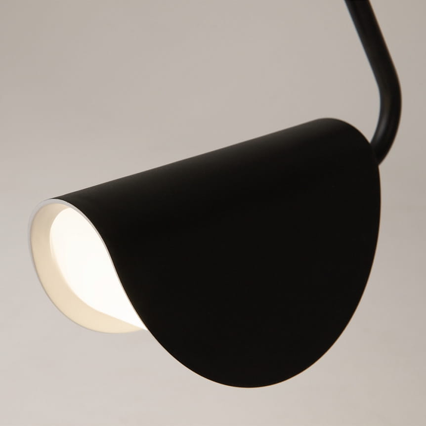Czarna lampa wisząca Mollis z kloszem w kształcie półkuli, wykonana z metalu. Widoczny jest detal wnętrza klosza w jasnym kolorze, który emituje światło. Ujęcie z bliska, ukazujące kąt i fakturę powierzchni.