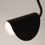 Czarna lampa wisząca Mollis z kloszem w kształcie półkuli, wykonana z metalu. Widoczny jest detal wnętrza klosza w jasnym kolorze, który emituje światło. Ujęcie z bliska, ukazujące kąt i fakturę powierzchni.