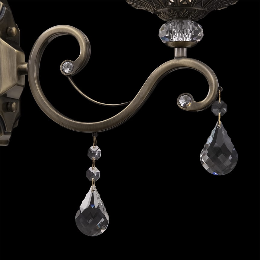 Kinkiet Grace 1-punktowy w kolorze patyny. Elegancka, zakrzywiona podstawa z dekoracyjnymi kryształkami, w tym wiszącymi kroplami. Wysoka jakość materiałów, idealny do oświetlenia wnętrz.