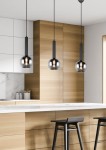 Czarna lampa wisząca Clayton 1-punktowa z metalowym, szklanym kloszem w kształcie kuli. Zawieszona na cienkim przewodzie, w nowoczesnej aranżacji kuchennej z drewnianymi szafkami i białym blatem.
