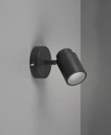Czarna lampa sufitowa Angelo IP44 z pojedynczym spotem GU10, zamontowana na ścianie. Okrągła podstawa i ruchomy klosz o matowej fakturze, skierowany lekko w dół. Tło w neutralnym odcieniu szarości.