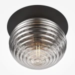 Czarna lampa sufitowa Reels z oprawą na żarówkę E27. Szklany klosz z wypukłą fakturą, okrągły kształt, zamontowana na czarnej podstawie. Zbliżenie na źródło światła wewnątrz klosza.