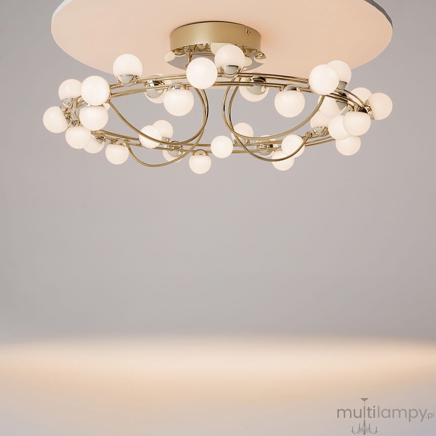 Lampa sufitowa LED Tessara w kolorze złotym, z 55W mocy i temperaturą barwową 3000K. Okrągła konstrukcja z białymi, szklanymi kulami rozmieszczonymi na cienkich, złotych ramionach. Ujęcie z dołu, pokazujące detal i kształt lampy.