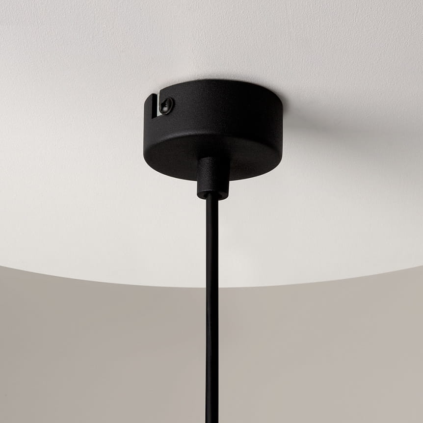Czarna lampa wisząca Ross z oprawą na jedną żarówkę GU10. Widoczna metalowa podsufitka oraz czarny przewód. Lampa ma transparentny klosz, który rozprasza światło. Ujęcie z dołu, pokazujące połączenie z sufitem.