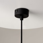 Czarna lampa wisząca Ross z oprawą na jedną żarówkę GU10. Widoczna metalowa podsufitka oraz czarny przewód. Lampa ma transparentny klosz, który rozprasza światło. Ujęcie z dołu, pokazujące połączenie z sufitem.