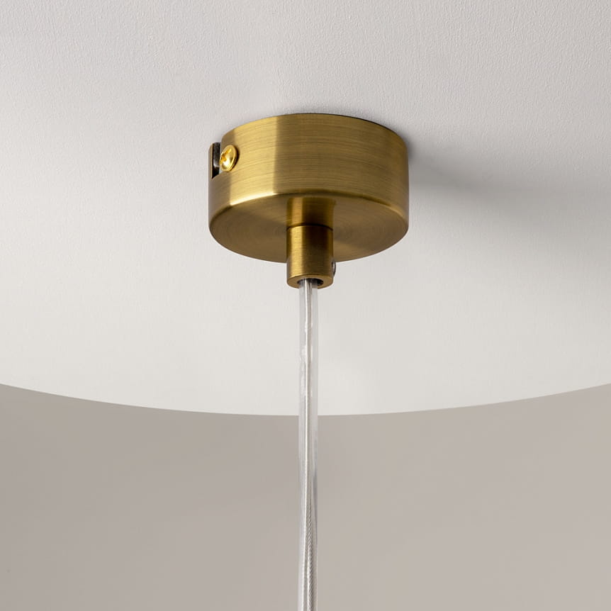 Lampa wisząca Ross z mosiężnym wykończeniem i przezroczystym przewodem. Widok z góry na sufitowe mocowanie z mosiądzu, z widocznym elementem montażowym. Prosty, elegancki design pasujący do nowoczesnych wnętrz.