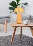 Pomarańczowa lampa stołowa Lennon LED o kształcie grzyba, wykonana z matowego materiału. Ustawiona na drewnianym stoliku, obok białej filiżanki. Tło z rośliną i szarym dywanem tworzy przytulną atmosferę.