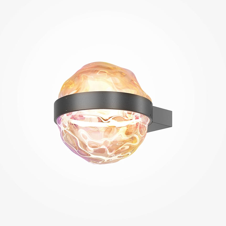 Kinkiet LED Misterio o mocy 6W, barwie światła 2700K, w kolorze czarnym. Posiada zaokrągloną, szklaną klosz o falistym wzorze w odcieniach różu i złota, zamontowany na prostokątnej, czarnej podstawie. Ujęcie z boku.