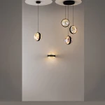 Lampa wisząca LED Misterio w kolorze czarnym, z sześcioma okrągłymi kloszami w przezroczystym wykończeniu, emitującymi ciepłe światło (2700K). Powieszona na długich linkach, w minimalistycznym wnętrzu na szarym tle.