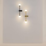 Kinkiet LED Touch w kolorze czarnym, moc 13W, temperatura barwowa 3000K. Ułożony na ścianie, z okrągłymi kloszami w górnej i dolnej części. Obok znajduje się kinkiet w kolorze złotym, tworzący nowoczesną aranżację.