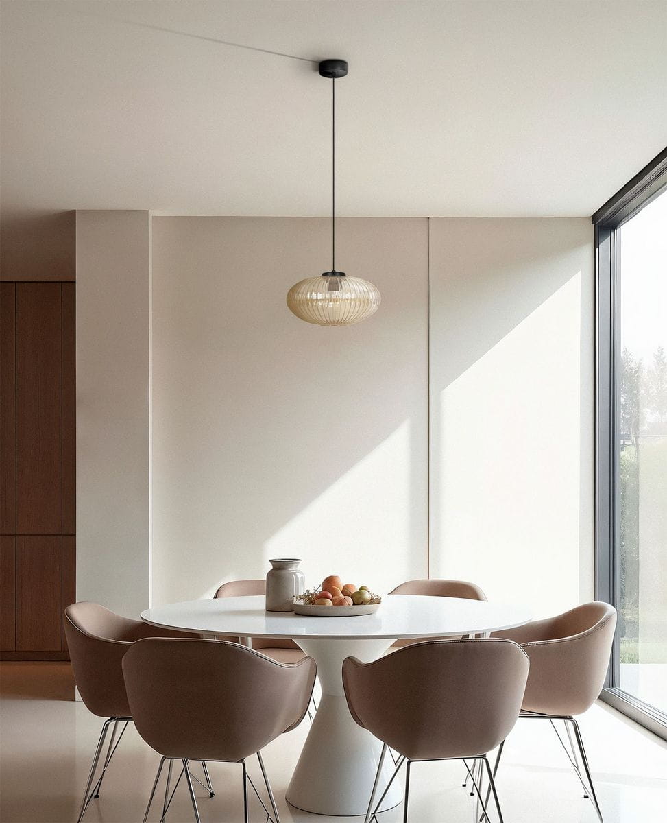 Lampa wisząca Drop 1xE27 w kolorze czarnym z bursztynowym kloszem, zawieszona na cienkim przewodzie w nowoczesnej kuchni. Widoczne okrągłe kształty oraz minimalistyczny design, otoczenie z białym stołem i brązowymi krzesłami.