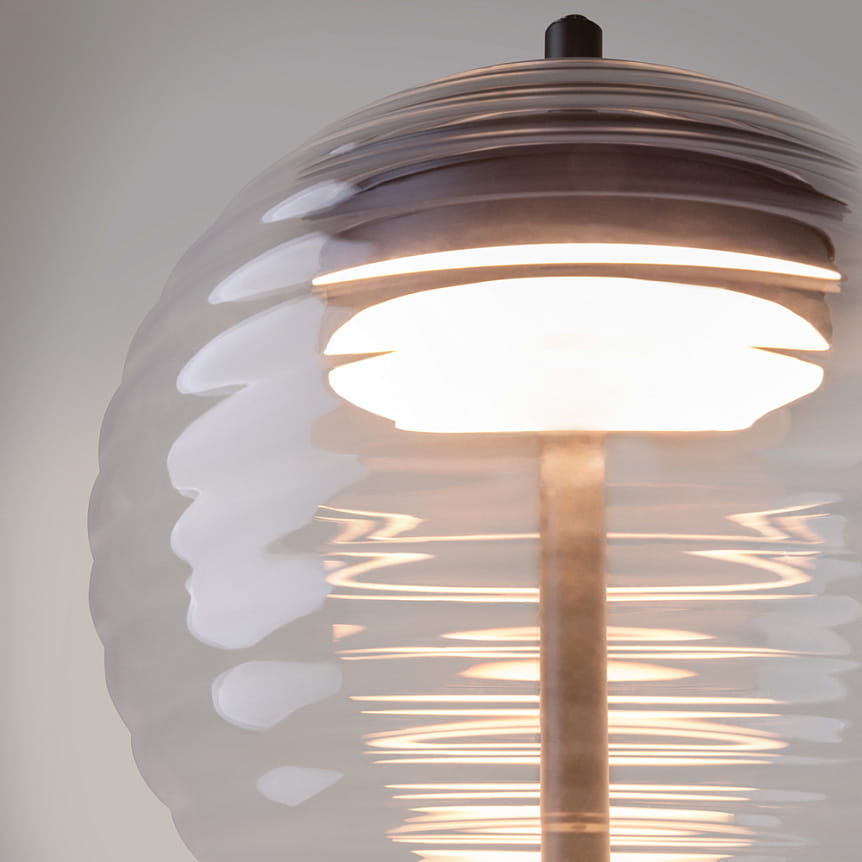 Lampa stołowa LED Mystic o mocy 8W i barwie światła 3000K, w kolorze czarnym, z przezroczystą, falistą kloszem, pokazana w zbliżeniu. Klosz eksponuje ciepłe światło emitowane przez źródło, osadzone na metalowym stelażu.