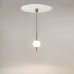 Lampa wisząca LED The Sixth Sense, mosiężna, z białym kloszem w kształcie kuli, zawieszona na cienkim czarnym przewodzie. Elementy metalowe w kolorze mosiądzu, okrągła, biała podsufitka. Temperatura barwowa 3000K, moc 7W.