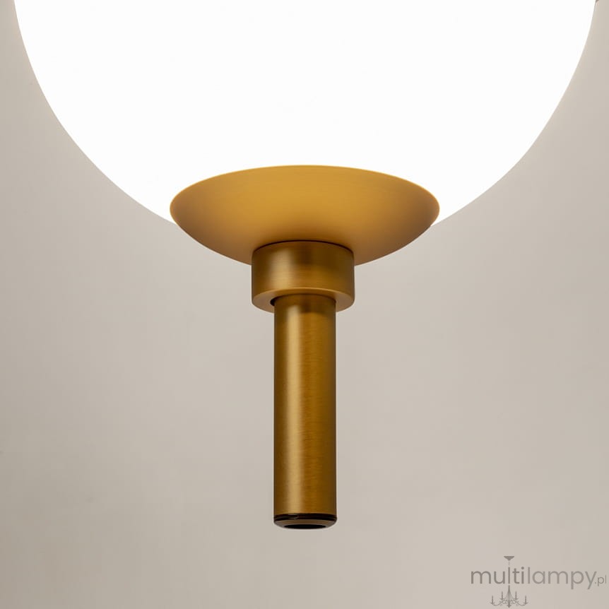 Lampa wisząca LED The Sixth Sense w kolorze mosiądzu, z okrągłym, białym kloszem. Ujęcie z dołu pokazujące detal mocowania i metalowy słupek. Wbudowana żarówka 7W, temperatura barwowa 3000K. Tło neutralne.