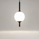 Lampa wisząca LED The Sixth Sense o mocy 7W, barwie światła 3000K, z czarnym metalowym uchwytem. Okrągła, mleczna kula z tworzywa sztucznego zawieszona na cienkim przewodzie, prezentująca minimalistyczny design na jasnym tle.