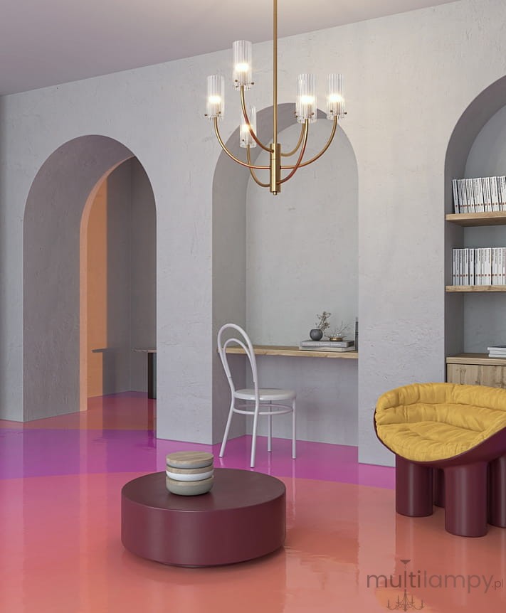 Lampa wisząca Arco w kolorze mosiądzu z trzema źródłami światła G9, umieszczona w nowoczesnym wnętrzu. Lampa ma elegancką konstrukcję z przezroczystymi kloszami, zawieszona na długim, cienkim przewodzie. W tle widać stół i krzesło.