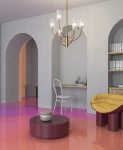 Lampa wisząca Arco w kolorze mosiądzu z trzema źródłami światła G9, umieszczona w nowoczesnym wnętrzu. Lampa ma elegancką konstrukcję z przezroczystymi kloszami, zawieszona na długim, cienkim przewodzie. W tle widać stół i krzesło.