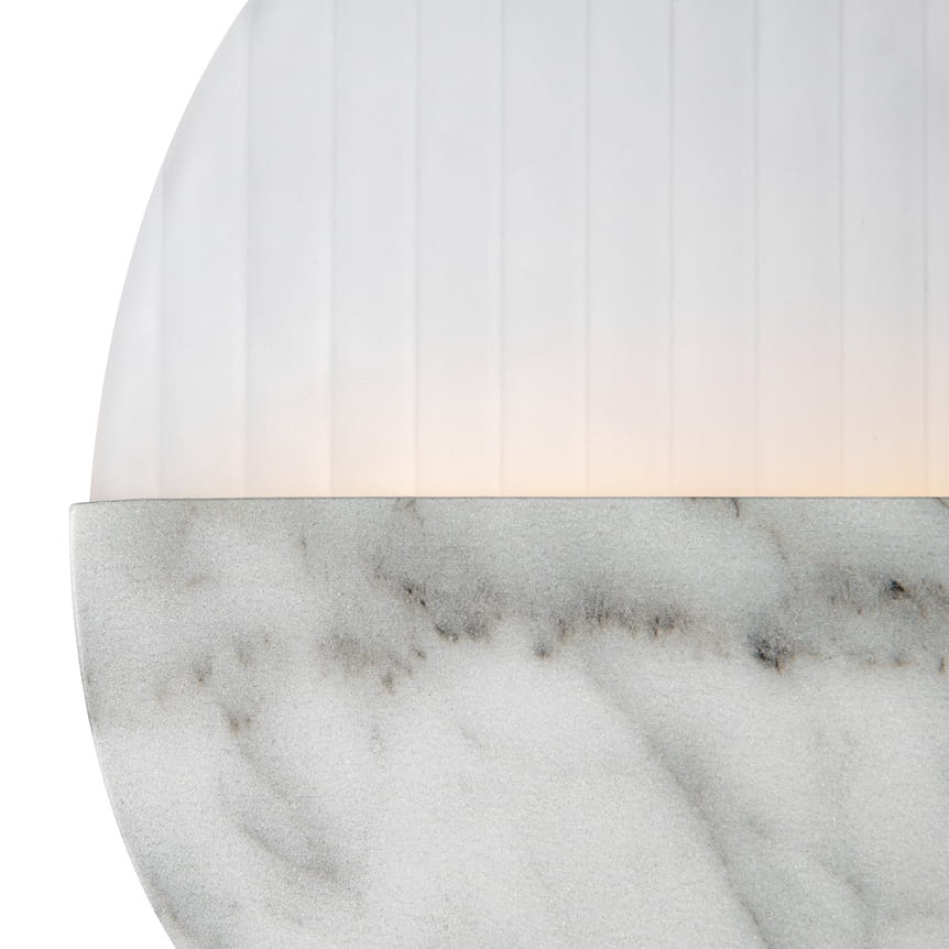 Lampa ścienna Jupiter D30 z marmurową podstawą i oprawą z matowego szkła. Górna część ma pionowe żłobienia, emitując ciepłe światło (3000K). Produkt widoczny z przodu, eksponujący szczegóły faktury marmuru.