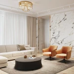 Lampa sufitowa Frame 9xE14 w kolorze złotym, z geometrycznym kształtem, zamontowana na suficie. W tle widoczny nowoczesny salon z beżową sofą, pomarańczowymi fotelami, oknem z zasłonami i marmurową ścianą.