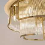 Lampa sufitowa Frame 9xE14 w kolorze złotym, o zaokrąglonym kształcie z przezroczystymi, żłobkowymi kloszami. Widoczne żarówki w eleganckiej oprawie. Ujęcie z dołu, ukazujące detal konstrukcji i efekt świetlny.