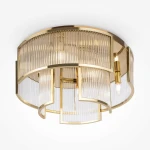 Lampa sufitowa Frame z sześcioma miejscami na żarówki E14, w kolorze złotym. Okrągła konstrukcja z przezroczystymi, pionowymi przesłonami, układającymi się w faliste wzory. Ujęcie z góry, na białym tle.