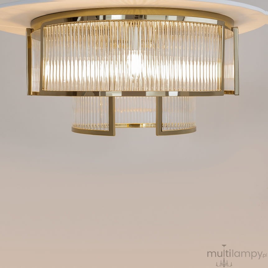 Lampa sufitowa Frame 6xE14 w kolorze złotym, z dekoracyjnymi, przezroczystymi kloszami o żłobionej fakturze. Ujęcie z góry, ukazujące elegancki design i źródła światła wewnątrz. Prosta, jasna aranżacja tła.