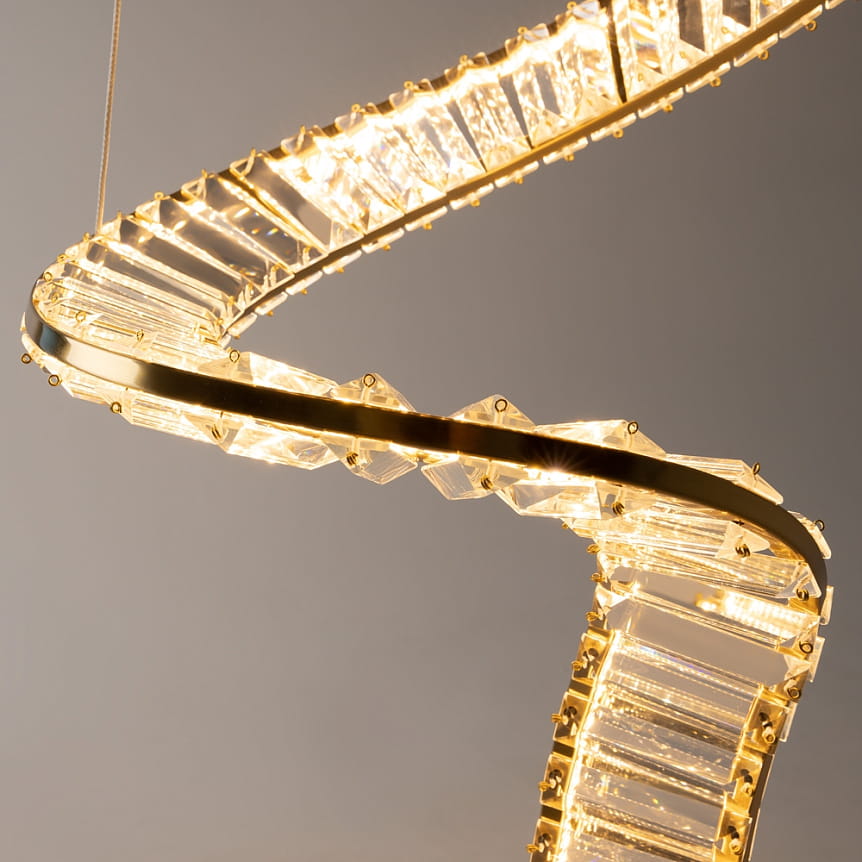 Lampa wisząca LED Krone o mocy 48W i temperaturze barwowej 3000K, wykonana z mosiądzu. Posiada unikalny, spiralny kształt z przezroczystymi akcentami, zawieszona na cienkich linkach. Idealna do nowoczesnych wnętrz.