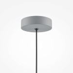 Szara lampa wisząca Basic Color z oprawą na jedną żarówkę E27. Prosty, okrągły klosz z fakturą, zawieszony na cienkim, czarnym przewodzie. Lampa wisi w centralnej pozycji, na jasnym tle, co podkreśla jej minimalistyczny design.