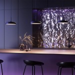 Lampa wisząca LED Gerhard w kolorze czarnym, moc 19W, temperatura barwowa 3000K. Ujęcie z boku, zawieszona nad blatem, w tle efektowna, połyskująca ściana. Oświetlenie tworzy atmosferę w nowoczesnym wnętrzu.