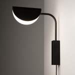 Kinkiet Mollis 1-punktowy w kolorze czarnym, z okrągłym kloszem w kształcie półksiężyca, zamontowany na ścianie. Lampa ma prosty, minimalistyczny design z metalowym ramieniem i prostokątną podstawą. Oświetlenie skierowane w dół.