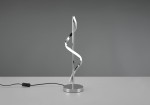 Isabel LED lampa stołowa 1-punktowa w chromowanej obudowie, z falującym kształtem. Produkt stoi na okrągłej, metalowej podstawie. Widoczny czarny przewód z włącznikiem. Tło w odcieniach szarości.