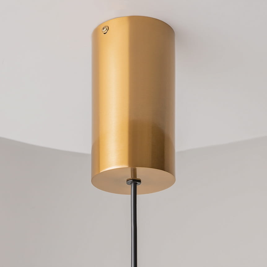 Lampa wisząca LED Imaginary w kolorze złotym, o cylindrycznym kształcie, z metalicznej powierzchni. Posiada czarny kabel zasilający. Ujęcie z dołu, ukazujące mocowanie do sufitu. Ciepła barwa światła 3000K, moc 5W.