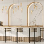 Lampa wisząca LED o mocy 5W i barwie światła 3000K w złotym kolorze, zawieszona w stylowym wnętrzu. Widoczne kilka lamp wzdłuż sufitu nad nowoczesnym barem z marmurowym blatem i krzesłami z czarnymi metalowymi nogami.