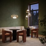 Lampa wisząca Levitation 1xG9 w mosiężnej oprawie, z przezroczystym kloszem, zawieszona w nowoczesnym wnętrzu. Widoczne dwa okrągłe stoliki oraz stylowe krzesła w odcieniu brązu. Tło w zieleni z oknem, przez które wpada naturalne światło.