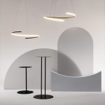 Lampa wisząca LED Curve w kolorze mosiądzu, o mocy 31W, zawieszona w nowoczesnym wnętrzu. Dwa okrągłe źródła światła o minimalistycznym kształcie na tle geometrycznych form w odcieniach szarości. Wysokość lampy regulowana.