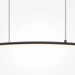 Curve lampa wisząca LED w kolorze czarnym, o długości łuku, z białą oprawą światła. Zawieszona na dwóch cienkich linkach, ukazuje nowoczesny design. Tło jasne, proste, podkreślające elegancję lampy.
