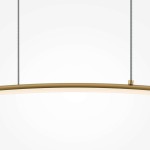 Lampa wisząca LED Curve w kolorze mosiężnym, o prostym, zakrzywionym kształcie. Zawieszona na dwóch cienkich przewodach, z delikatnym, białym źródłem światła w dolnej części. Tło neutralne, jasne.