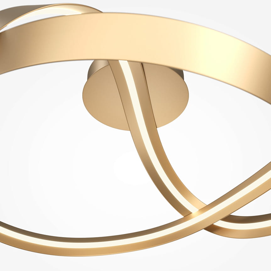 Lampa sufitowa LED Plons o mocy 34W, kolor mosiężny. Zawiera podświetlane, zakrzywione paski w kształcie fali, montowana do sufitu. Widok z bliska, ukazujący detale konstrukcji i połączenie z podstawą.