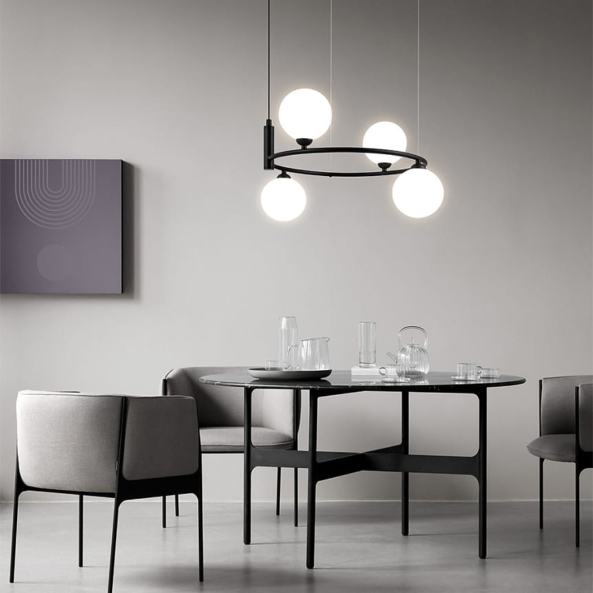 Czarna lampa wisząca Ring MOD013PL-04B z czterema okrągłymi kloszami na białym tle, zawieszona nad okrągłym stołem. Wnętrze w nowoczesnym stylu z szarymi krzesłami i minimalistycznymi dodatkami.