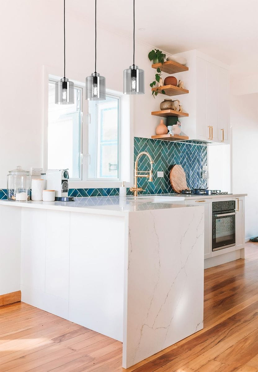 Luna lampa wisząca 1xE27 w kolorze czarnym i grafitowym, zawieszona nad kuchennym blatem. Lampa ma cylindryczny kształt, przezroczystą osłonę oraz widoczne żarówki, co podkreśla nowoczesny styl. Tło w jasnych kolorach z elementami drewnianymi.