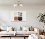 Lampa sufitowa Vanes w kolorze beżowym i bursztynowym, z pięcioma oprawkami E27. Kształt cylindryczny, z przezroczystymi kloszami, zamontowana na suficie w nowoczesnym wnętrzu, nad sofą. Tło jasne, z minimalistycznymi dekoracjami.