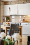 Lampa wisząca Aurelia 1xE27 w kolorze czarnym z bursztynowym kloszem, zawieszona na czarnym kablu. Widoczna w kuchni nad drewnianym stołem, otoczona szarymi krzesłami w kratę, z białymi ścianami i drewnianymi detalami.