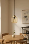 Lampa wisząca Iga z czarnym mocowaniem i bursztynowym kloszem, o prostokątnym kształcie, zawieszona na cienkim przewodzie. Widoczna w minimalistycznym wnętrzu z drewnianym stołem i książkami w tle.