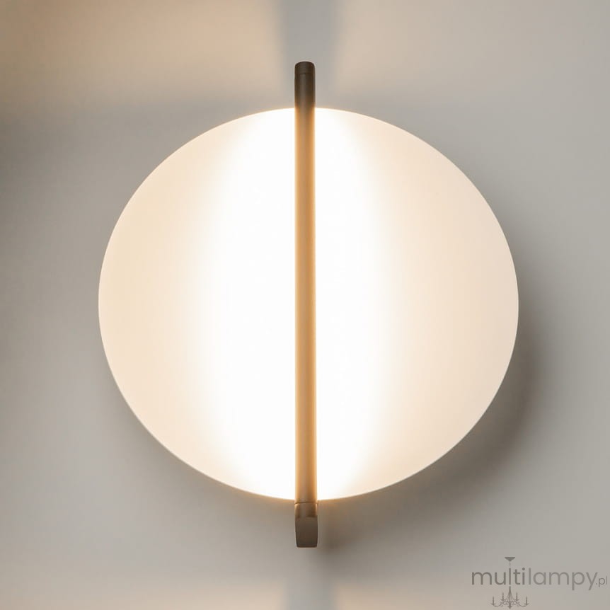Kinkiet LED Mira, moc 14W, kolor czarny. Okrągła, matowa obudowa z białego materiału oraz centralna, pionowa linia emitująca ciepłe światło (3000K). Zawieszony na ścianie, minimalistyczny design.