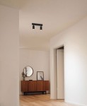 Czarna lampa sufitowa Monti z dwoma reflektorami GU10, zamontowana na suficie, w nowoczesnym wnętrzu. Reflektory skierowane w dół, na jasnym tle, obok drewniana komoda i okrągłe lustro.