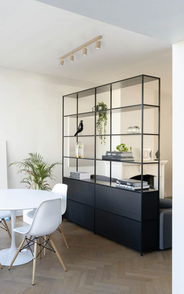 Beżowa lampa sufitowa typu spot Mati z czterema oprawami GU10, zawieszona na prostokątnej podstawie, umieszczona w minimalistycznym wnętrzu z otwartą półką i białym stołem.