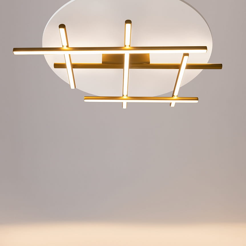 Lampa sufitowa LED Radiance o mocy 50W i temperaturze barwowej 3000K, z okrągłą, białą podstawą oraz złotymi, prostokątnymi elementami w układzie krzyżowym, wisząca w centralnej pozycji.