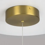 Złota lampa wisząca LED Radiance o mocy 80W, temperatura barwowa 3000K. Widoczna okrągła podsufitka z matowego metalu, z zawieszeniem na cienkim przewodzie. Prosty, elegancki design, idealny do nowoczesnych wnętrz.